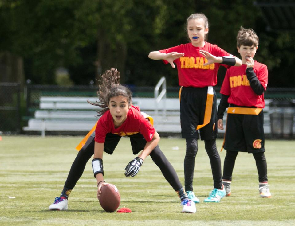Pemain flag football Trojans berjersey merah-emas saat snap